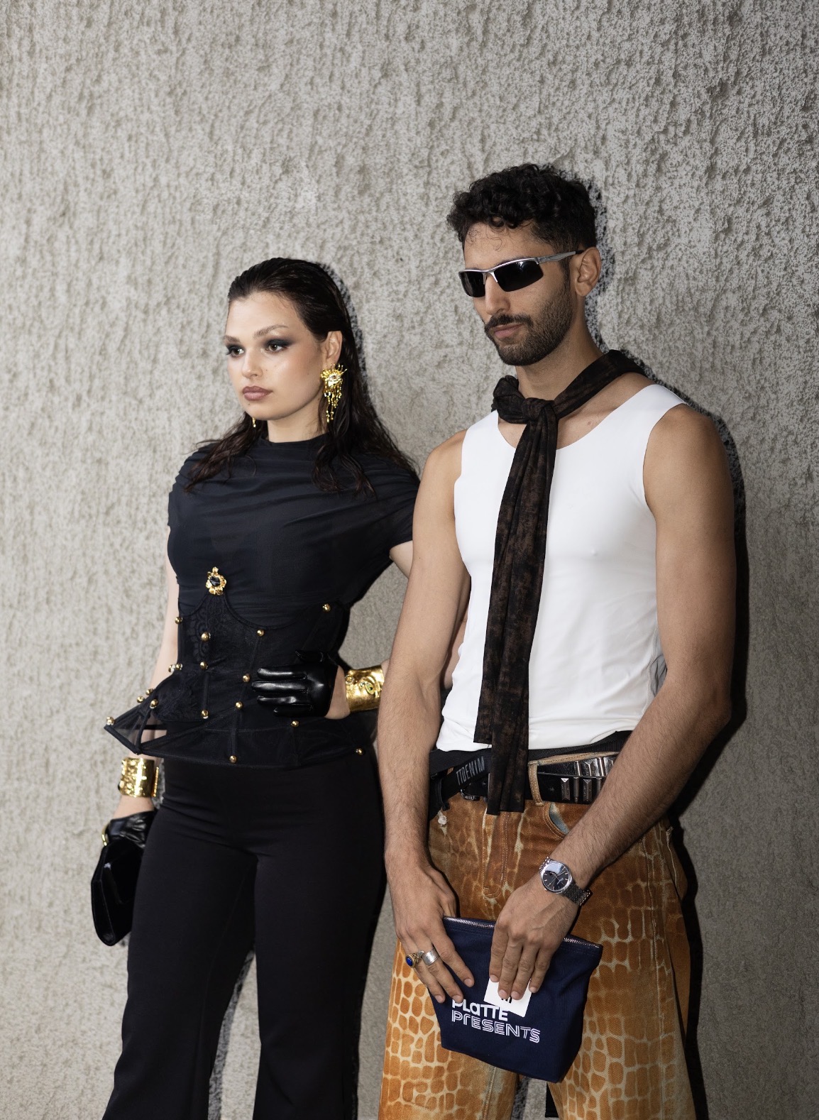 Adeline Frickel in a black corseted look beside a second model against a concrete wall
